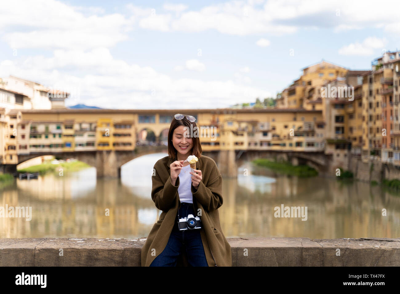 Italy, Florence, young tourist woman eating an ice cream cone at at Ponte Vecchio Stock Photo