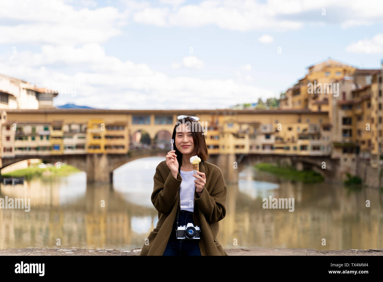 Italy, Florence, young tourist woman eating an ice cream cone at at Ponte Vecchio Stock Photo