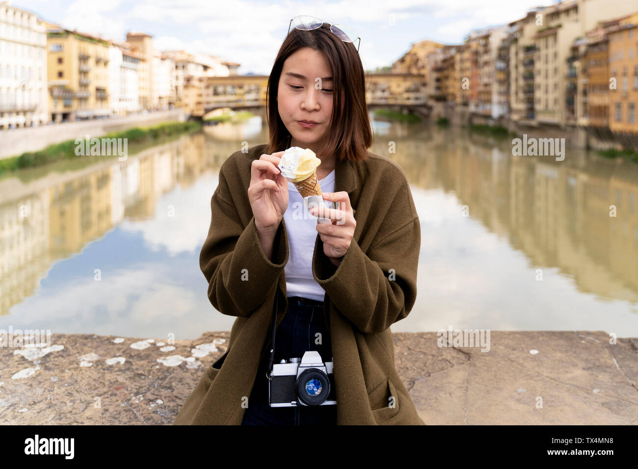 Italy, Florence, young tourist woman eating an ice cream cone at at Ponte Vecchio Stock Photo