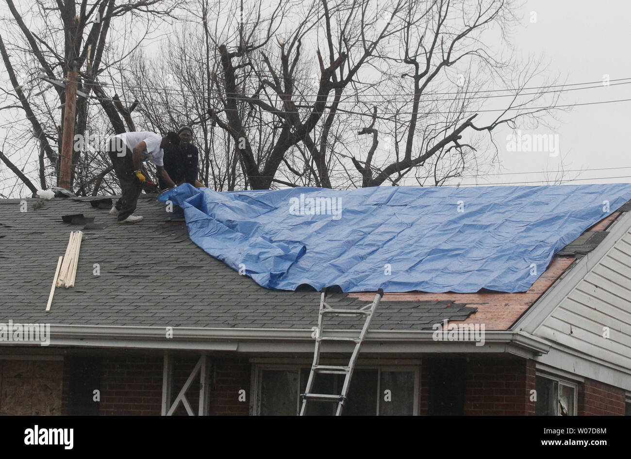 Workers attach a tarp to a roof on a house after a tornado ripped through this University City, Missouri neighborhood on April 3, 2014. The tornado which hit about 5:30 A.M. significantly damaged about 12 homes and did some damage to about 50 more. No injuries were reported.   UPI/Bill Greenblatt Stock Photo