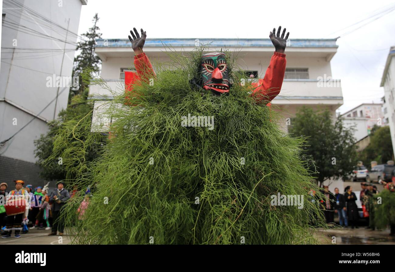 Chinese people of Miao ethnic group wearing masks and grassy cloaks dress up as the god to bring good luck to villagers during the Manggao Festival in Stock Photo