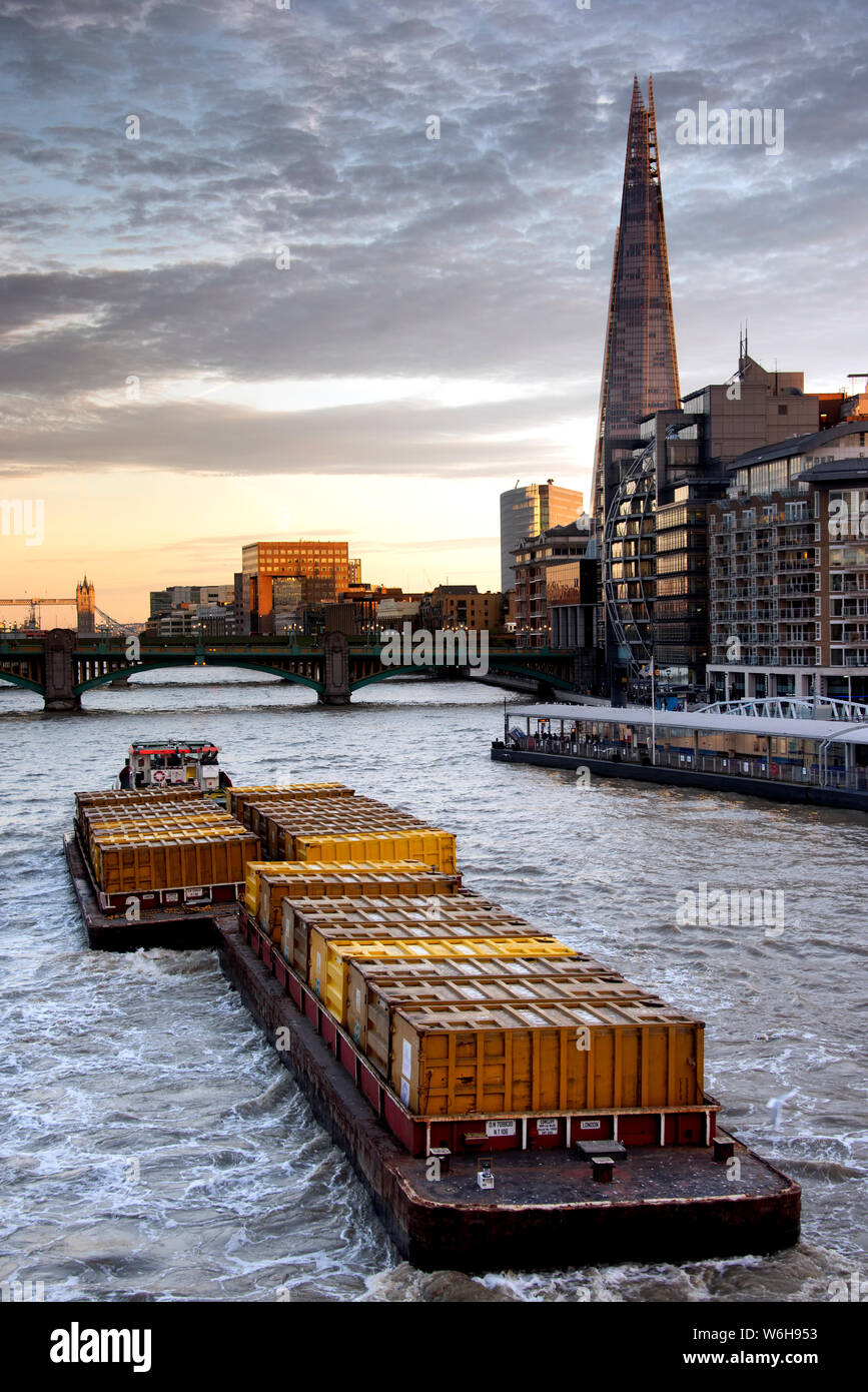 tug boat pulling cargo barge at thames river during evening Stock Photo