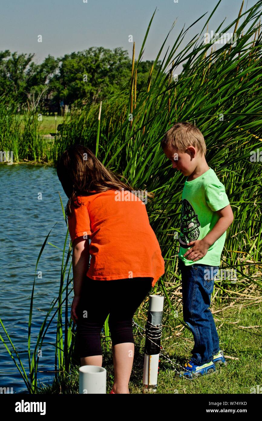 My Grandchildren, Salem, and Thomas Placing a Channel Catfish into Live Basquet, Lindsey City Park, Canyon, Texas. Stock Photo