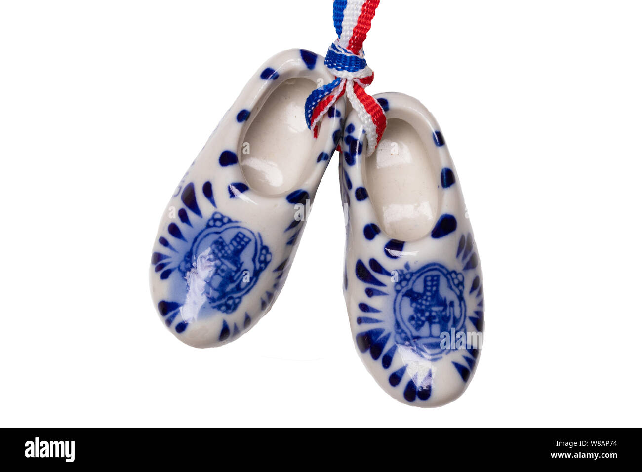 Holland wooden clogs. A pair of traditional dutch porcelain shoes with a ribbon flag isolated on a white background. Souvenir from Amsterdam. Macro. Stock Photo