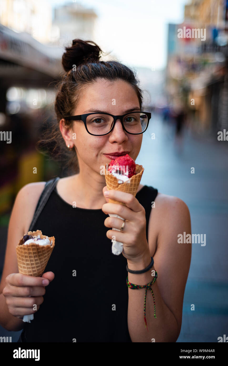 Cute hipster girl eating two ice creams on the street Stock Photo