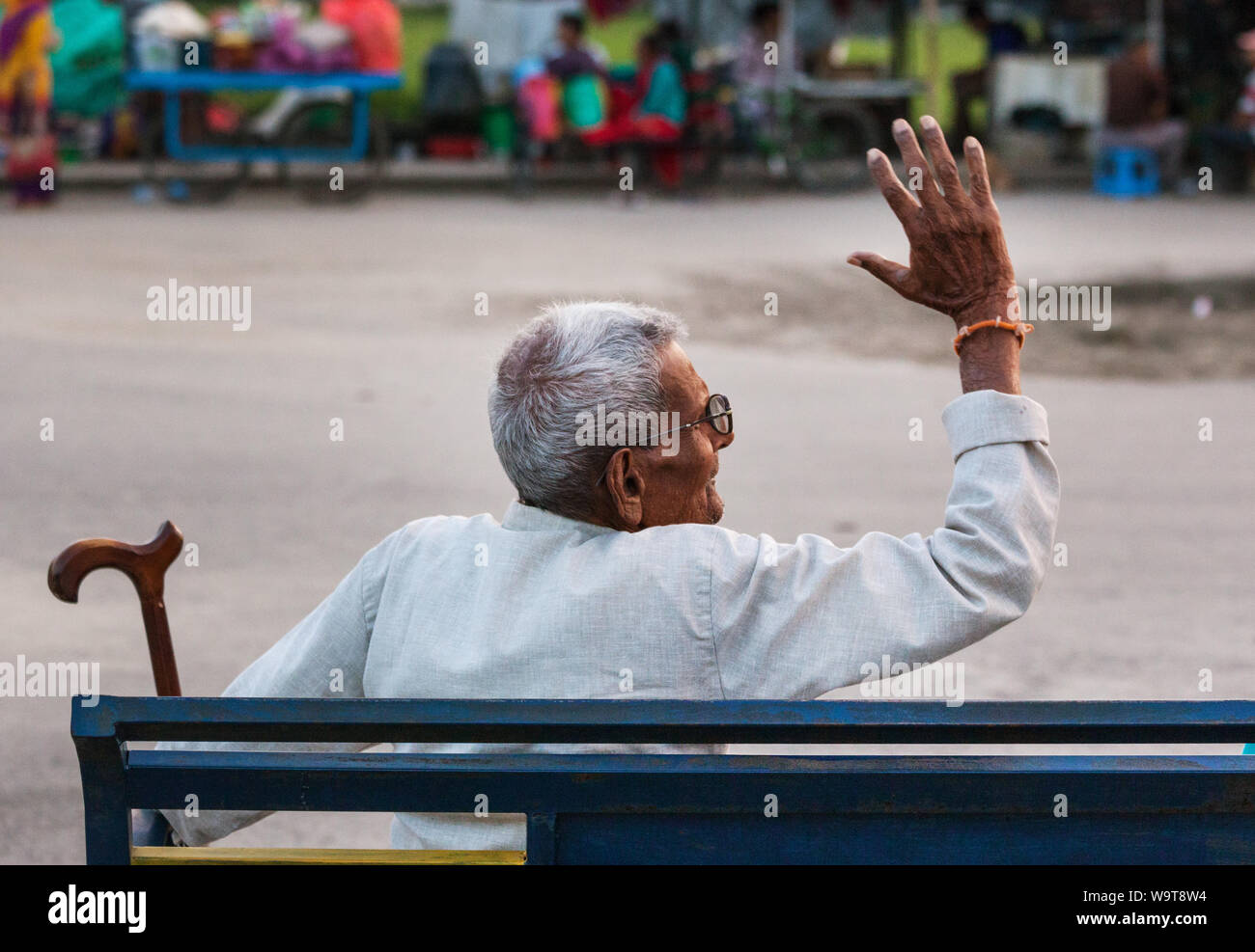 Old man sat on a park bench gestures with his arm while debating in Pokhara, Nepal. Stock Photo