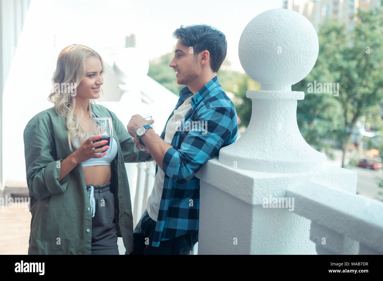 Couple standing on balcony in the morning and drinking coffee Stock Photo