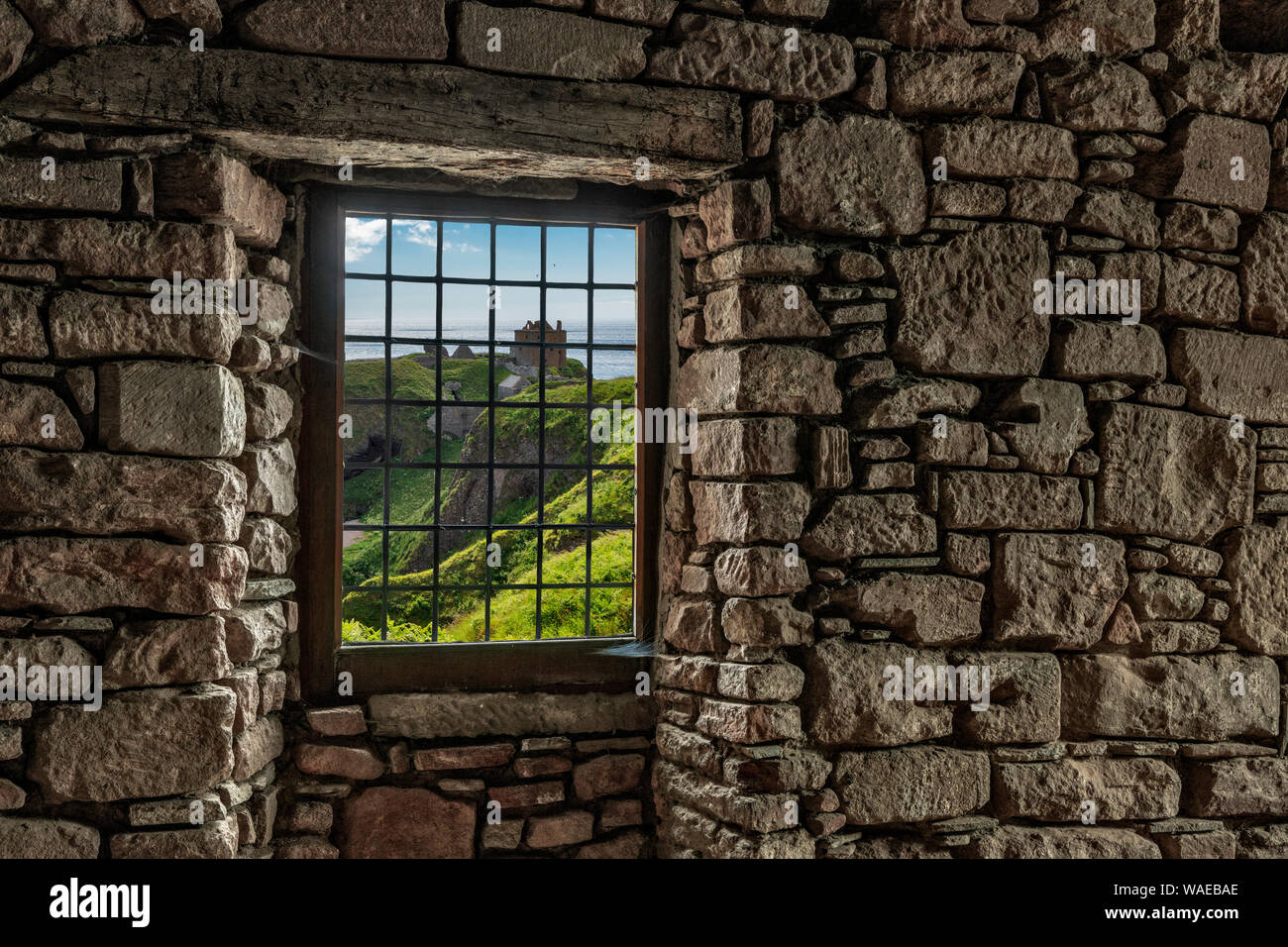 Looking through a window in a stone wall to the Dunottar Castle, Scotland Stock Photo