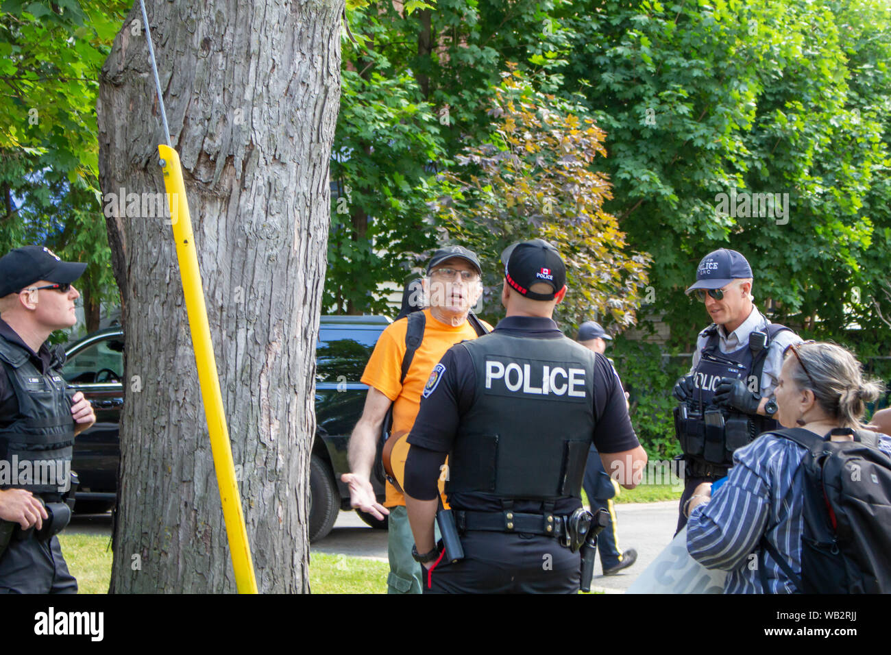 OTTAWA, ONTARIO, CANADA - August 23, 2019: An activist protesting Brazilian inaction in Ottawa converses with officers from the RCMP and local police. Stock Photo