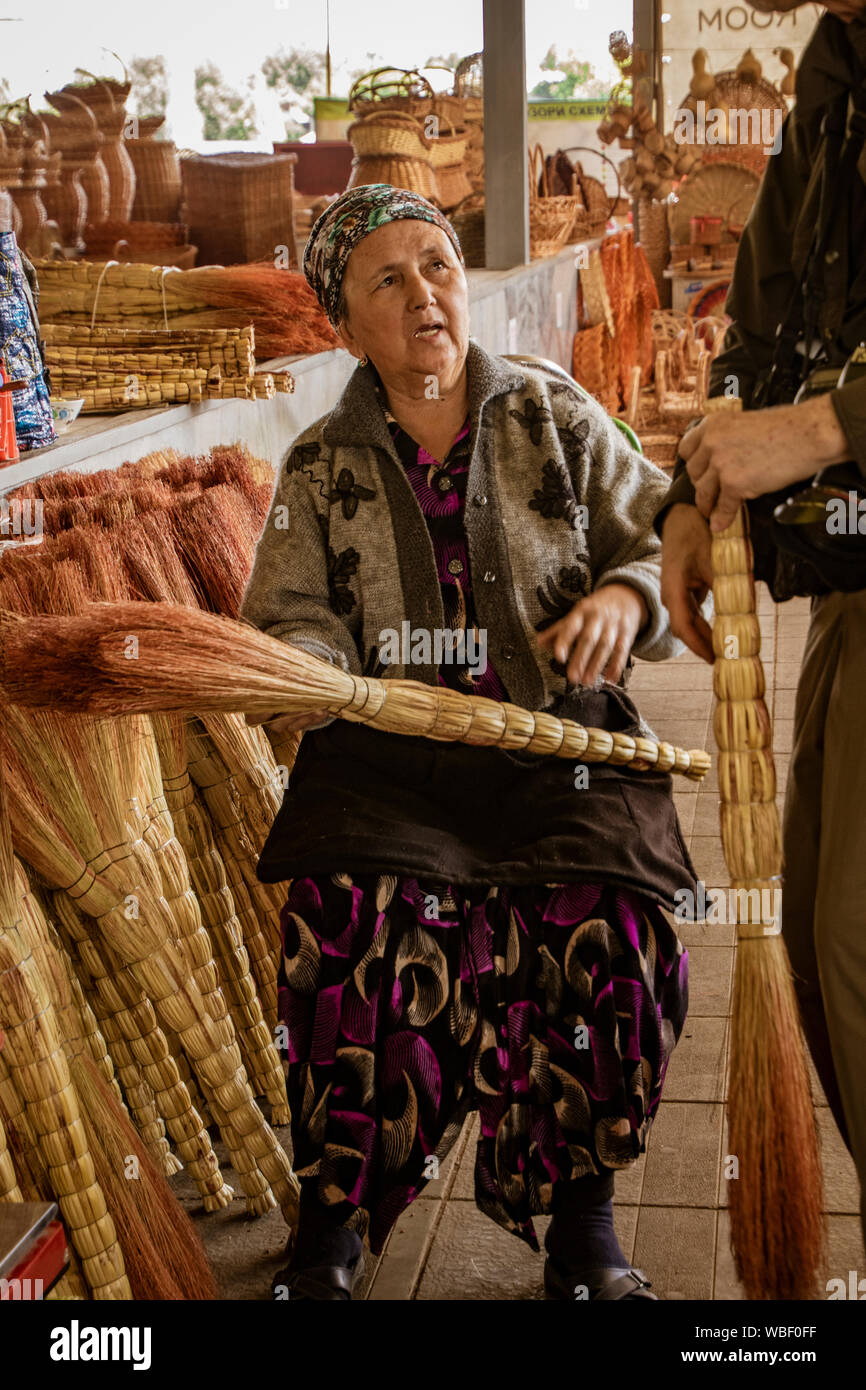 Tashkent, Uzbekistan - May 18, 2018 - Customer negotiates to purchase hand-made broom from vendor Stock Photo