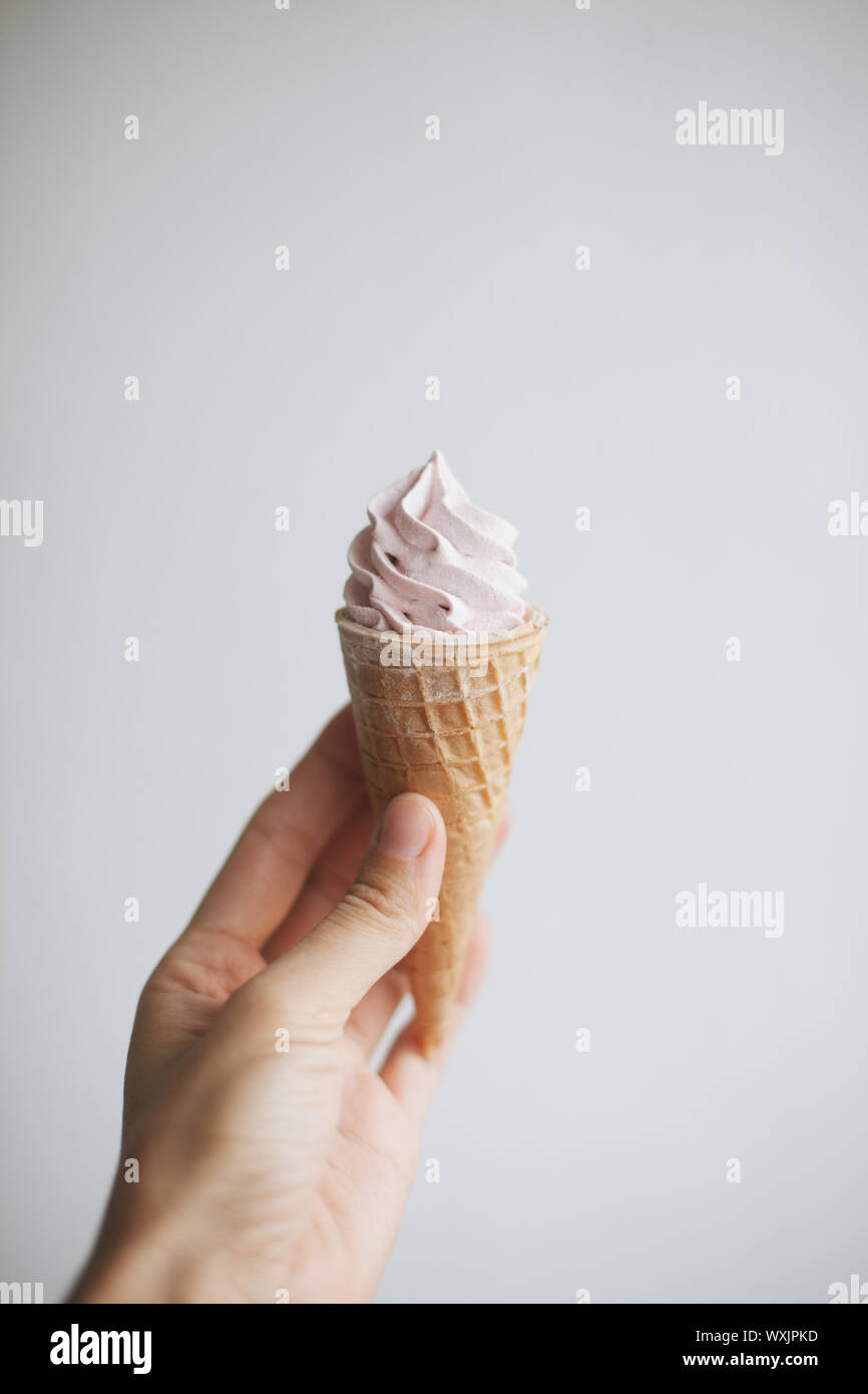 Woman's hand holding a waffle cone with whipped cream Stock Photo