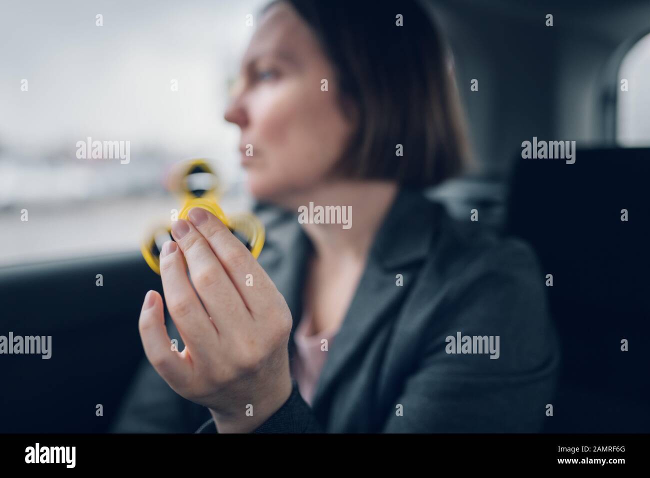 Geschäftsfrau spielen mit zappeln Spinner im Auto sitzend auf der Rückbank des Fahrzeugs und das Pendeln zum Arbeitsplatz, selektiven Fokus Stockfoto