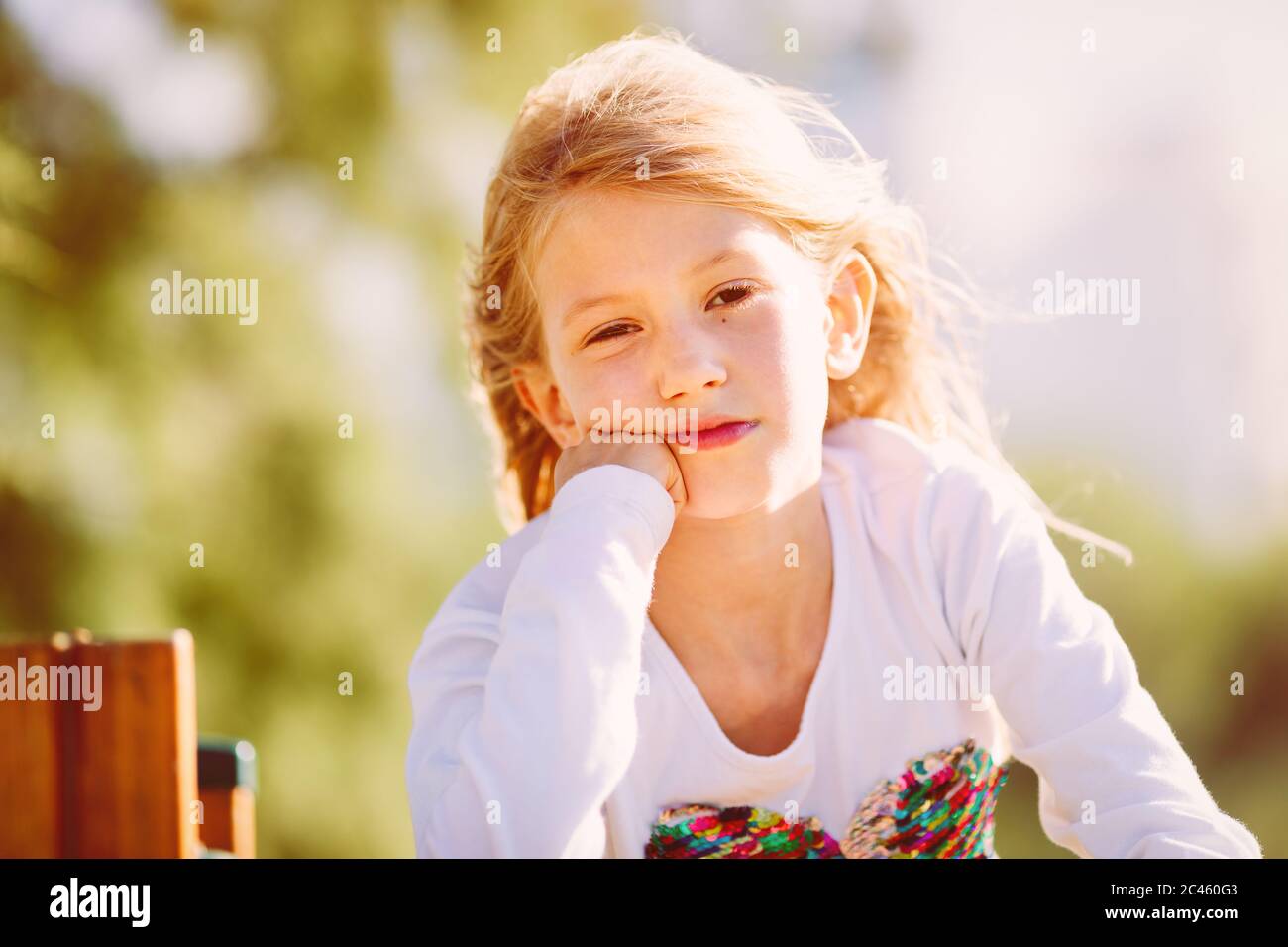 Porträt eines niedlichen Mädchen, Grundschulalter, mit blonden Haaren fliegen im Wind Stockfoto