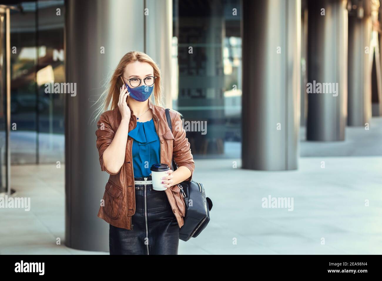 Frau trägt Gesichtsmaske reden am Telefon im Freien während der Pendelverkehr Stockfoto