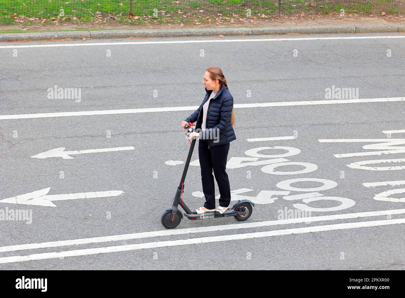 Eine Frau, die von der Arbeit nach Hause pendelt, auf einem elektrischen Roller in New York City Stockfoto