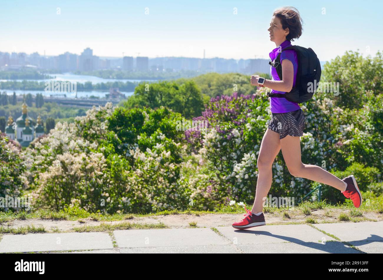 Active Woman Runner Run pendelt zur Arbeit mit Rucksack, City Morning Run pendeln und gesundes Lifestyle Konzept, Skyline von Kiew, Ukraine Stockfoto