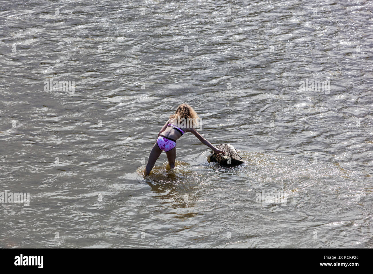 Ein Mädchen hinten, allein im Badeanzug, der in einem Fluss steht Stockfoto