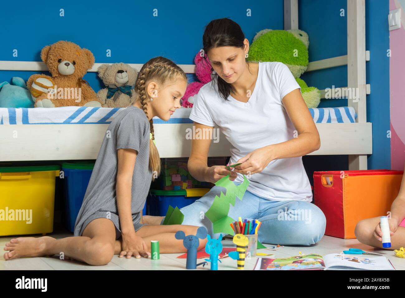 Mamá ayuda a mi hija recortar figuras de papel coloreado Fotografía de  stock - Alamy