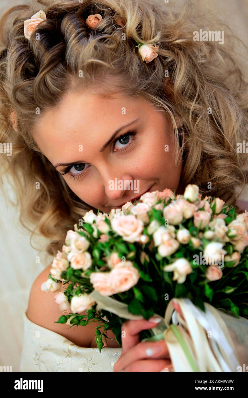 Une belle blonde bride vu ici dans une robe de mariage qui sent son bouquet de fleurs le jour de son mariage Banque D'Images