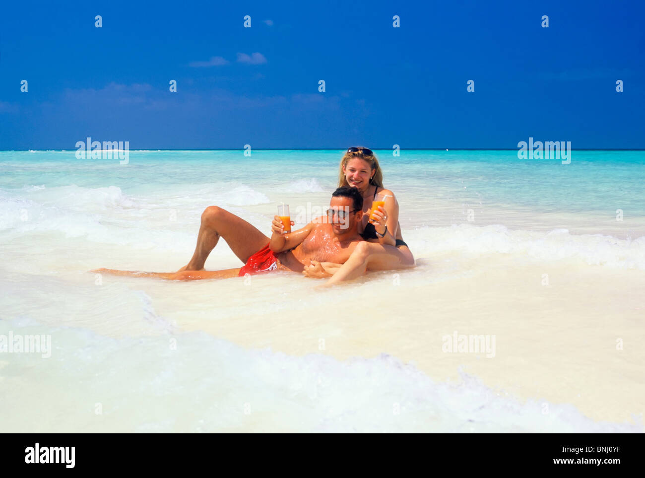 Couple paire 2030 locations de vacances Maldives voyage seashore beach disposent d'une baignoire d'eau de mer boisson bikini homme mari femme vagues Banque D'Images