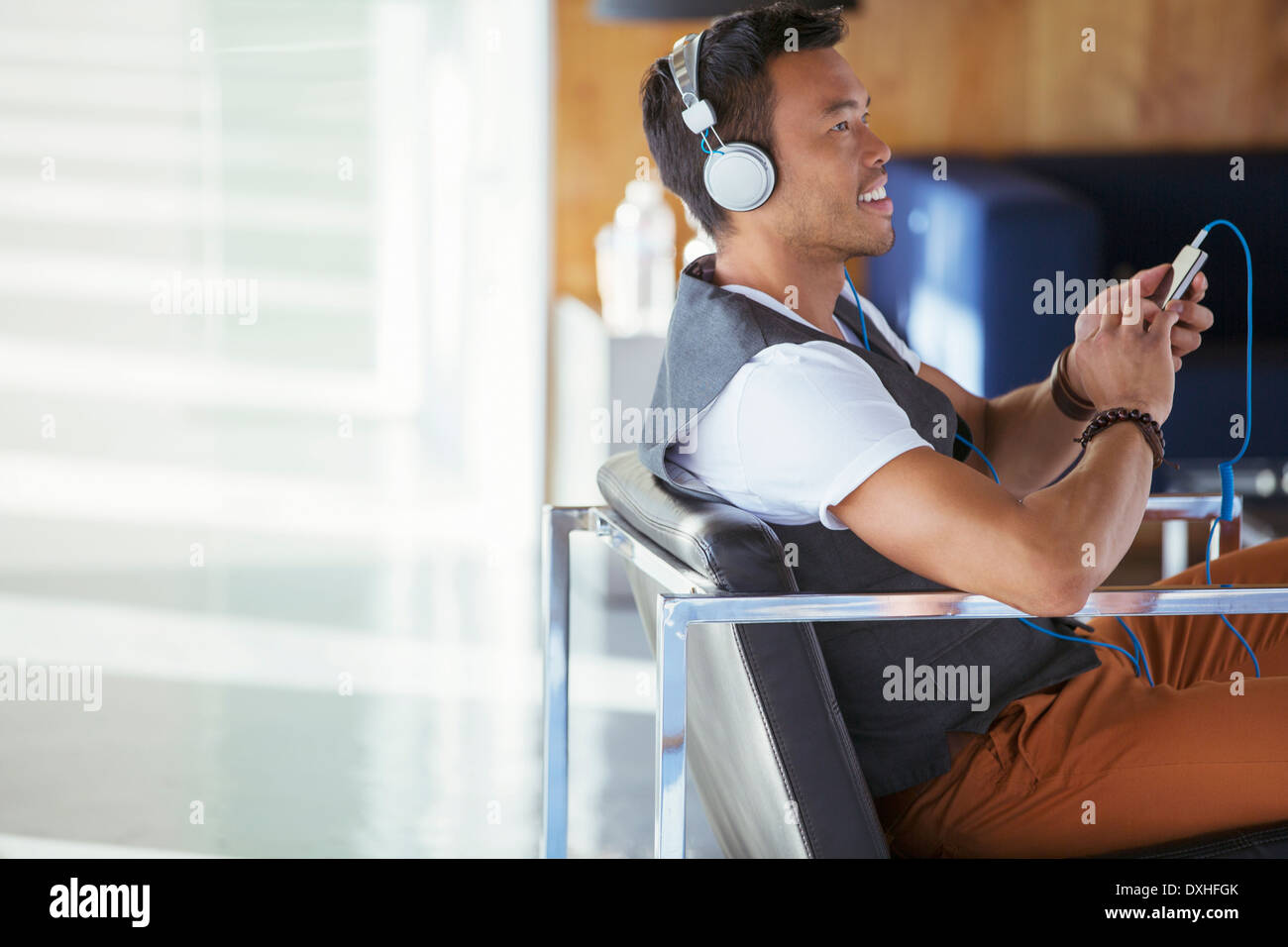 Smiling businessman écouter de la musique sur un lecteur mp3 avec des écouteurs Banque D'Images