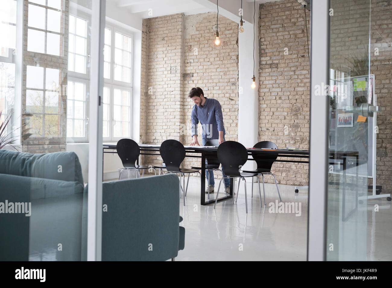 Jeune entrepreneur debout dans son bureau, à la recherche de plans à Banque D'Images