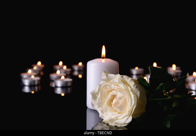 Burning candle and flower on black background Stock Photo - Alamy