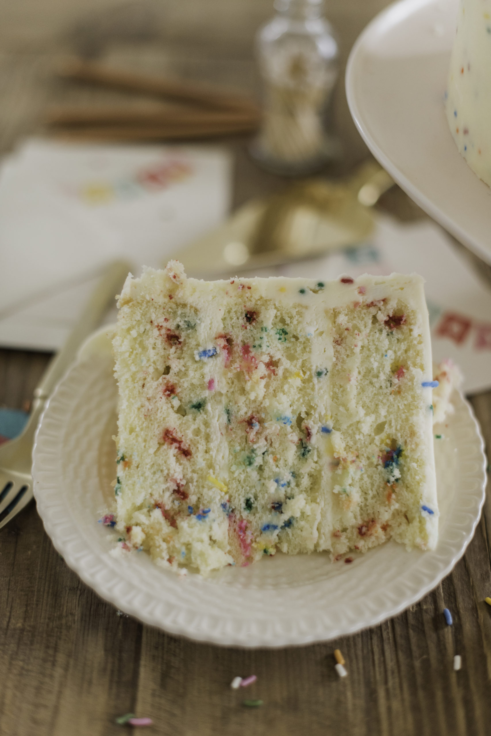 Classic Confetti Cake - tender and fluffy vanilla cake layers, filled with sprinkles and covered with a whipped vanilla buttercream. #confetticake #birthdaycake #bestbirthdaycake #funfetticake #birthdaycakerecipe #vanillabuttercream #cakebycourtney