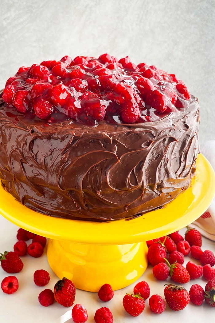 Raspberry Cake With Chocolate Ganache Frosting And Raspberry Pie Filling on Yellow Cake Stand