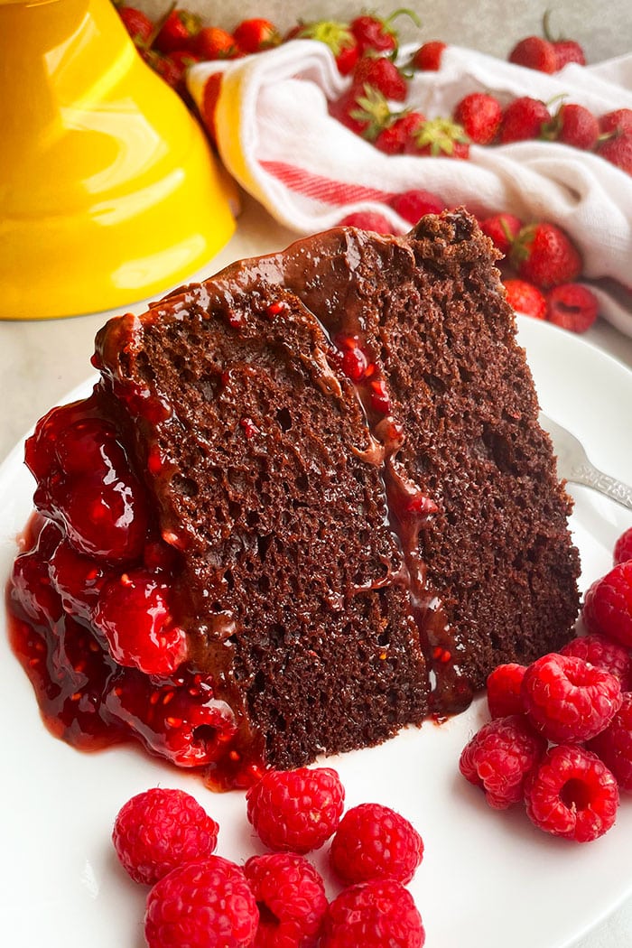 Slice of Summer Cake on White Plate With Raspberries and Strawberries Scattered Around