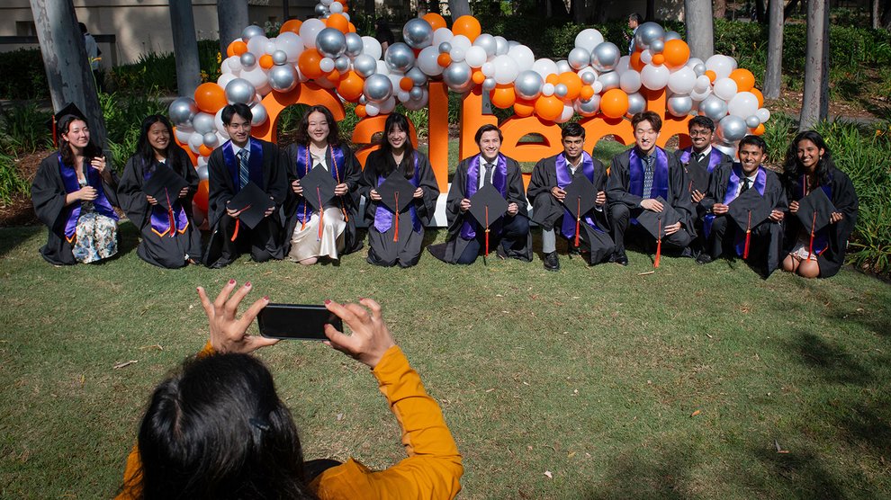 Graduates with purple Avery House stoles pose for a photo with a Caltech sign.