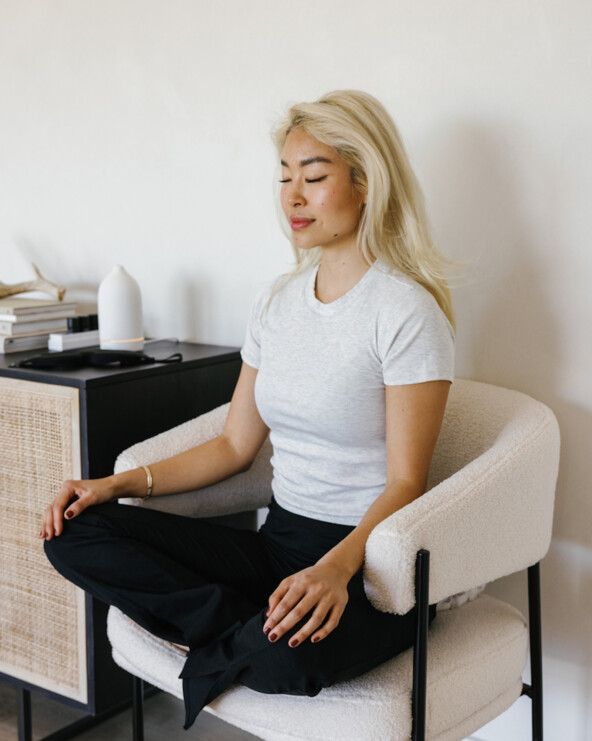 Woman doing somatic breathwork in chair.