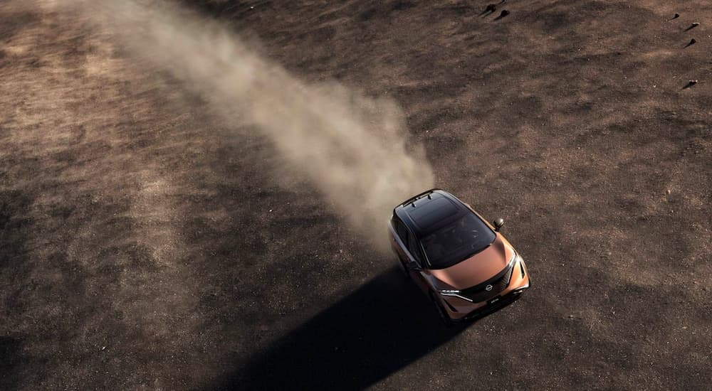 A bronze 2023 Nissan Ariya is shown from a high angle while driving off-road.