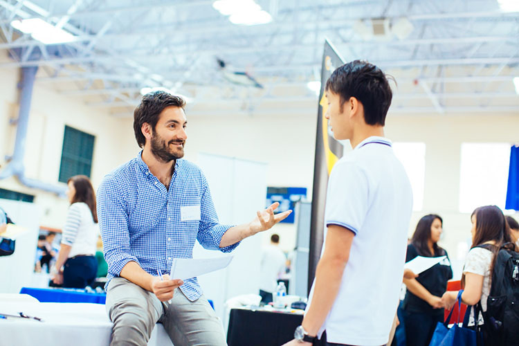  A student and an employer having a conversation at a networking event or career fair.