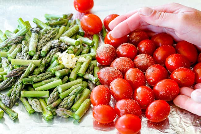 showing how to make Shrimp scampi in the oven by tossing tomatoes and asparagus on a baking sheet