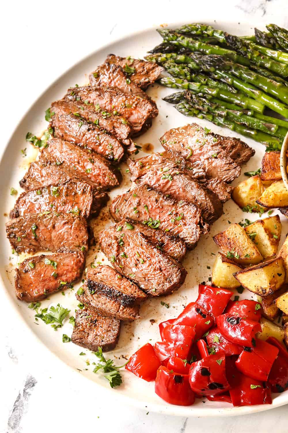 top view of sliced grilled sirloin steak on a white platter