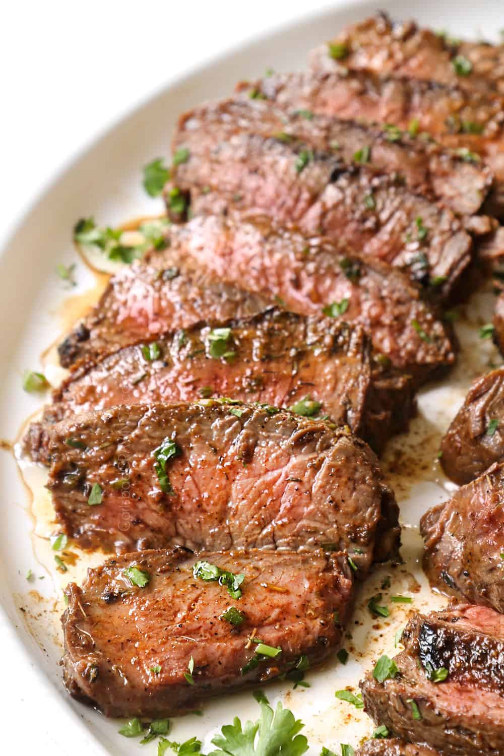 up close of sliced grilled steak lined on a platter showing what temp to cook it