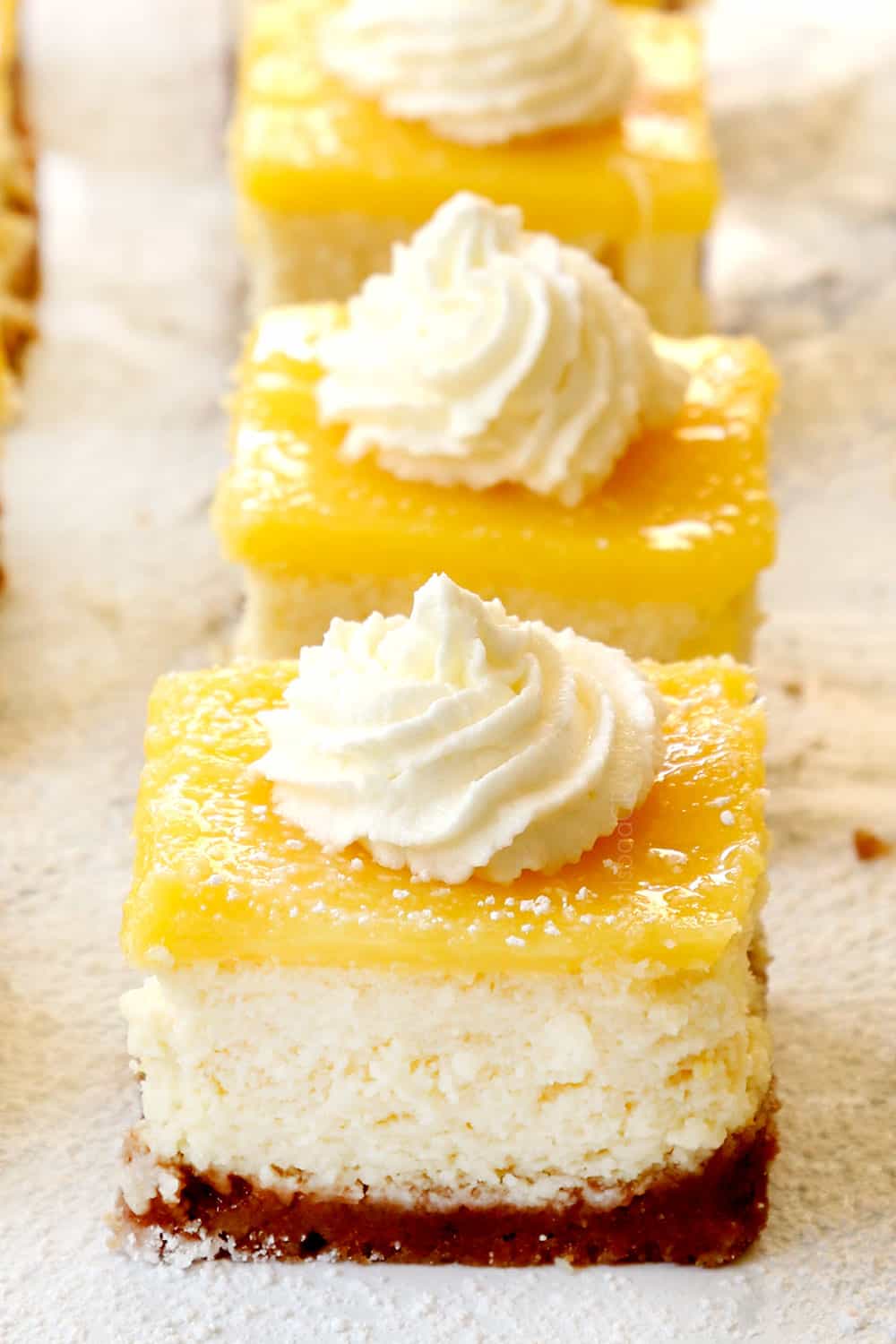 lemon cheesecake bars lined up on a marble counter