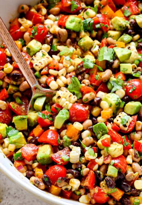 Texas Caviar being served in a bowl with a spoon garnished by cilantro