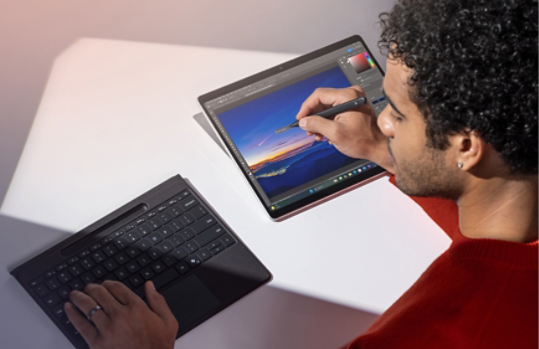 분리된 Surface Pro Flex Keyboard와 슬림 펜을 사용해 Surface Pro에서 사진을 편집하는 사람.