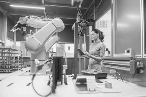 A worker programming a robotic arm using a tablet computer--an example of workplace automation.