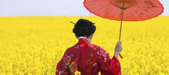 A young woman walks through a field of flowers