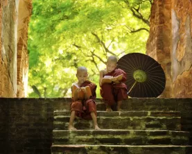 Two young monks read on the steps of a temple