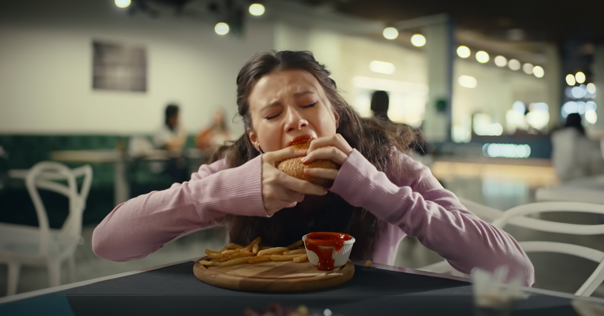 Girl frantically eats a burger | Source: YouTube/LoveBuster