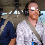 Two men in the cockpit of a single-engine plane during flight.