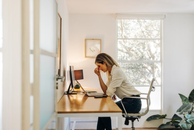 Woman holding her forehead while working at a home office