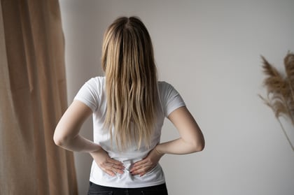 Woman holding her lower back in discomfort, indicating SI joint pain