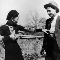 Bonnie Parker mockingly points shotgun at Clyde Barrow. American bank robbers and lovers Clyde Barrow (1909 - 1934) and Bonnie Parker (1911 -1934), popularly known as Bonnie and Clyde, circa 1933. criminal, thief, robbery team