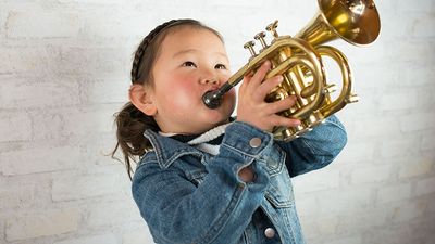 Young girl wearing a demin jacket playing the trumpet (child, musical instruments, Asian ethnicity)