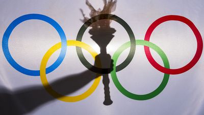 Silhouette of hand holding sport torch behind the rings of an Olympic flag, Rio de Janeiro, Brazil; February 3, 2015.